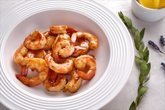 Fried shrimps in garlic sauce on a white plate with lemon
