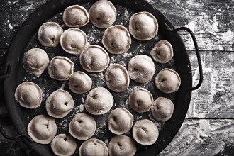 Handmade homemade dumplings on a decorative metal tray on a wooden background with flour. Diy meat dumplings