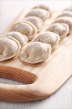 Handmade homemade dumplings on a wooden tray on a white plate with flour. Diy meat dumplings