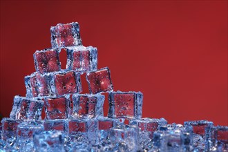 Transparent cold ice cubes on a red background