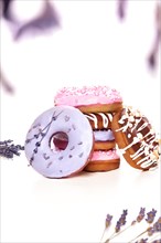 Sweet multicolored donuts on a white background with lavender flowers