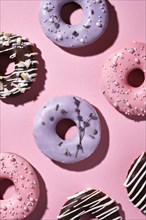 Sweet multicolored donuts on a purple background with lavender flowers