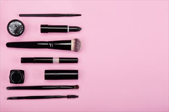 Set of brushes and cosmetic products on a pink background