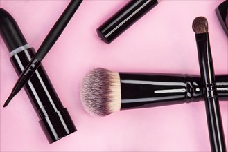 Set of brushes and cosmetic products on a pink background