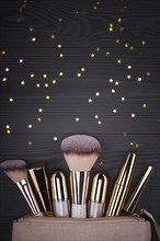 Set of brushes and cosmetic products in a cosmetic bag on a grey background