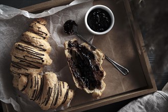 Croissants with chocolate and jam on a wooden breakfast tray