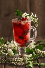 Berry soft drink with ice on a wooden background with flowers