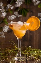 Orange fruit soft drink cocktail with ice on a wooden background with flowers