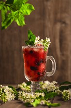 Berry soft drink with ice on a wooden background with flowers