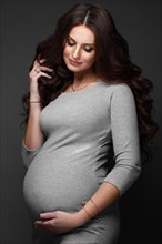 Beautiful pregnant woman in a gray dress