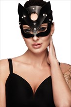 Beautiful woman pastry chef in cat mask and black dress