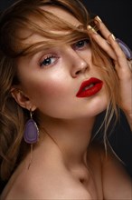 Beautiful girl with red lips and classic makeup and curls with large jewelry. Beauty face. Photo taken in the studio