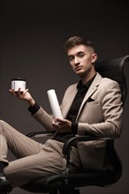 Handsome man hairdresser in a suit with a cosmetic in his hands. Photo taken in the studio