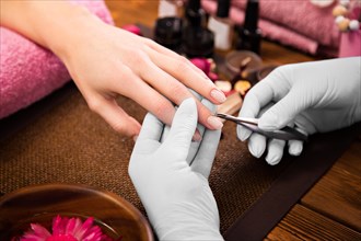 Closeup finger nail care by manicure specialist in beauty salon. Manicurist clear cuticle professional nippers for manicure and pedicure