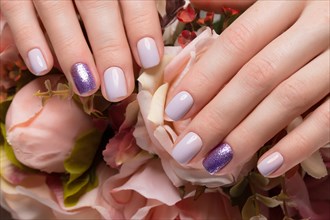 Purple neat manicure on female hands on a background of flowers. Nail design