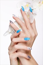 Beautiful summer blue manicure on female hand with flowers. Close-up. Picture taken in the studio