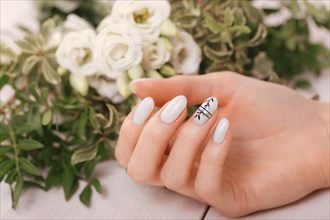 Gentle neat manicure on female hands on a background of flowers. Nail design