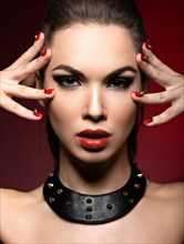 Beautiful woman in gothic style with evening makeup and red nails with thorns. Picture taken in a studio on a red background
