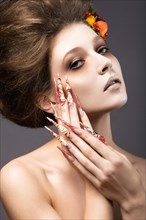 Beautiful girl in autumn image with long nails with bright and unusual make-up. Picture taken in the studio on a gray background