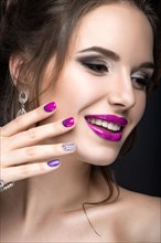Beautiful girl with a bright evening make-up and purple manicure with rhinestones. Nail design. Beauty face. Picture taken in the studio on a black background