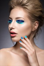 Beautiful girl with bright creative fashion makeup and blue nail polish. Art beauty nail design. Picture taken in the studio