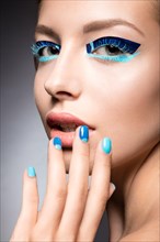 Beautiful girl with bright creative fashion makeup and blue nail polish. Art beauty nail design. Picture taken in the studio