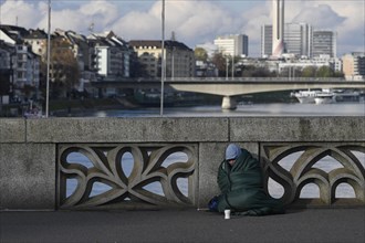 Homeless person with sleeping bag and cup