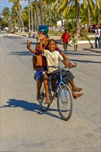 Happy boys cycling through the streets of Toliara