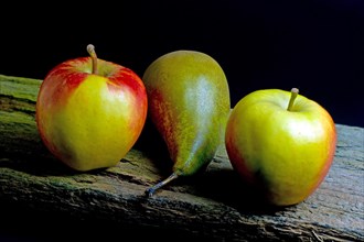 Two apples and a pear on an old wooden beam