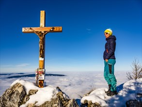 Mountaineer standing at the summit cross of the Mahdlgupf in the snow