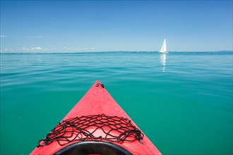 Bow of red kayak with view over the expanse and turquoise waters of Lake Constance