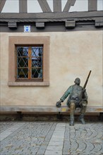 Sculpture Man sitting with rifle in front of half-timbered house Weapons Museum and window