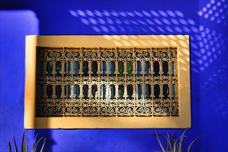 Ornate window grille in a blue wall