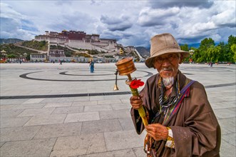 Pigrim with praying wheel before the Potala in Lhasa