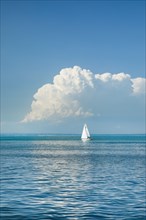White sailboat on the turquoise water of Lake Constance with a low