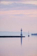 Lighthouse by the harbour wall at the Lake Geneva basin at pink dawn