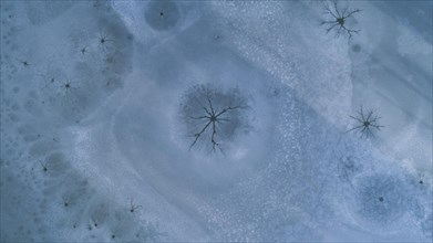 Drone image of so-called steam holes in the ice surface of a frozen lake caused by convection in the water