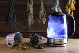 Electric kettle on wooden table with teas