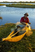 Fisherman repairs his net at sunset