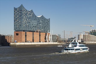 Excursion ship for harbour tours and Elbe Philharmonic Hall against a blue sky in the harbour of Hamburg