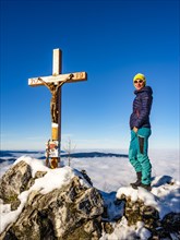 Mountaineer standing at the summit cross of the Mahdlgupf in the snow