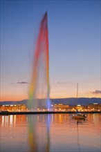 The illuminated Jet d'eau at dusk is the landmark in the Lake Geneva basin