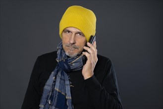 Elderly man with yellow winter cap on the phone