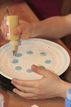 A child paints and decorates a plate