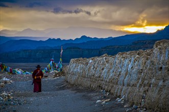 Monk walks along an eroded mud wall in the kingdom of Guge