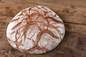 Round rye bread with a crispy crust and flour on an old table. Alsace
