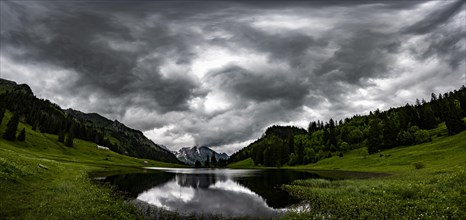 Groeppelensee with reflection of the Altmann summit in the background under a threatening cloudy sky