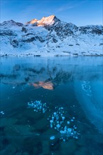 Frozen air bubbles in the black ice of the frozen Lago Bianco in the Swiss mountains