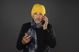 Elderly man with yellow winter cap excitedly talking on the phone