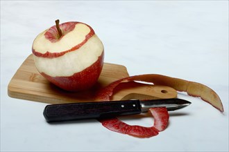 Peeled apple and apple peel with paring knife